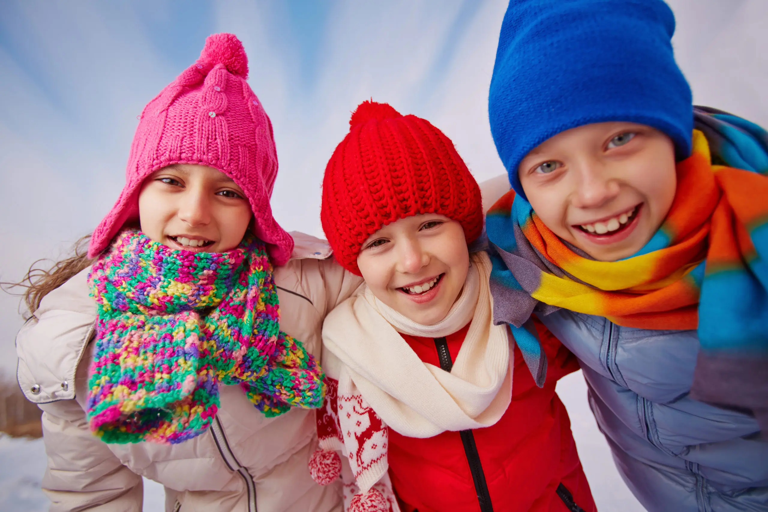 Joyful kids in winterwear looking at camera with smiles outside