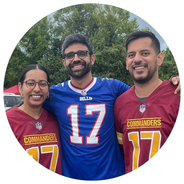 Three people are smiling outdoors, wearing football jerseys. Two jerseys are Commanders, one is Bills. Green trees are visible in the background.