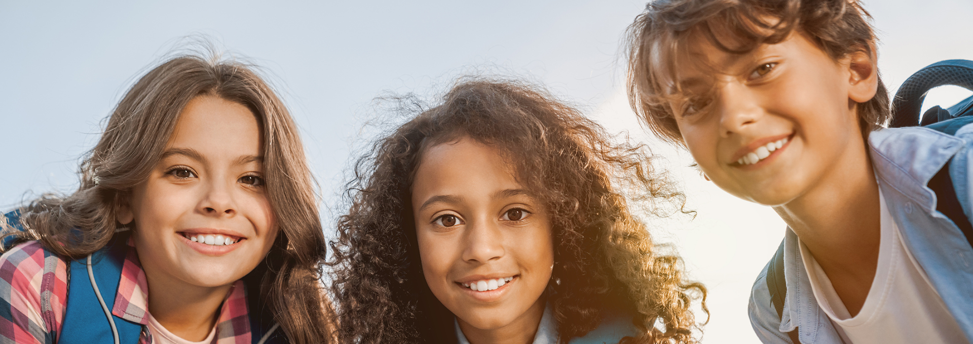 Three children smiling outdoors